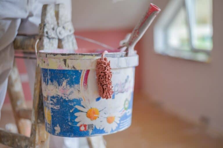 A closeup shot of a paint bucket hanging on a ladder
