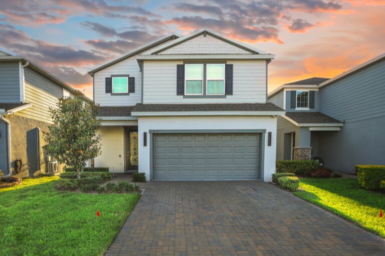An exterior shot of a white two-story house with a garage at sunset in ST Cloud, US.