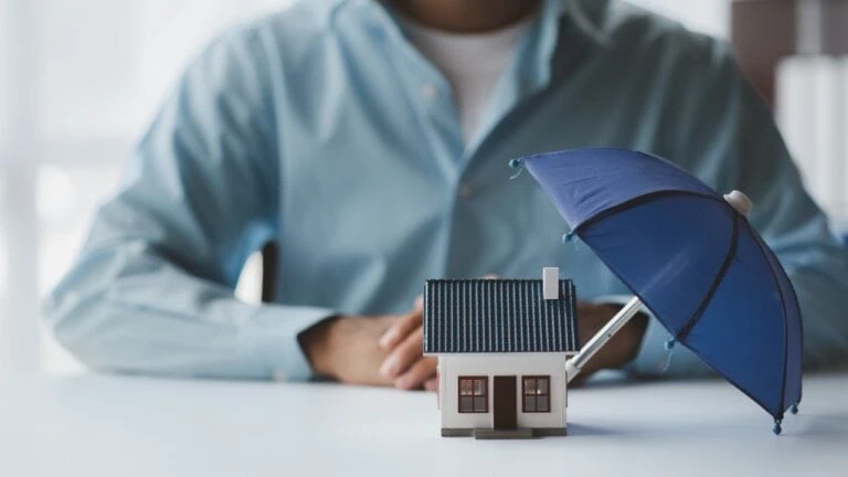 Individuals holding small umbrellas and model homes, housing insurance against impending loss and fire, building fire insurance, home and real estate insurance concepts.