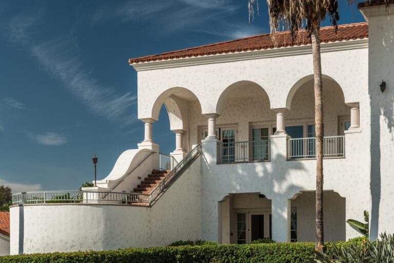 A white building with stairs and a palm tree