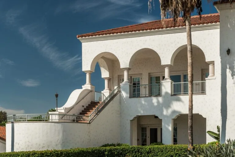 A white building with stairs and a palm tree