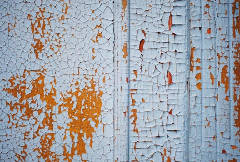Wooden wall with blue paint is severely weathered and peeling. close up