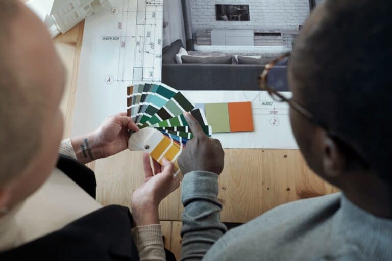 Young African male designer pointing at color palette while helping female colleague during work over new project